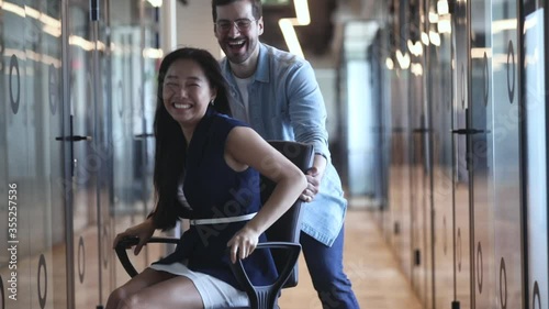 Fotografía Happy overjoyed business people have fun ride on chair in office hall, asian fem