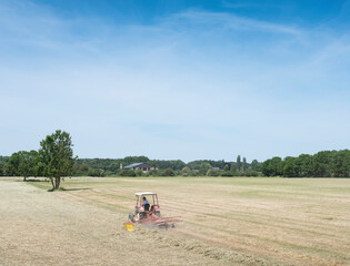 Poster - farmer in tractor shakes grass on sunny day between zutphen and deventer in holland