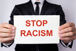 © VITAL - A man holds a white sheet of paper with the message in red letters STOP RACISM.