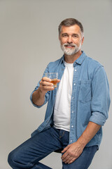 Wall Mural - Portrait of a casual senior sitting on a chair on white background.