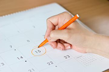 Female hand writing in calendar on 15th day of ovulation