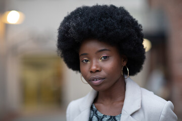 Young beautiful stylish curly woman in a business casual outfit on the street. Closeup.