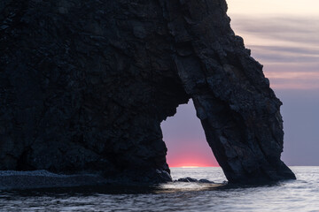 Wall Mural - The sun rises in a natural stone arch on the shore of Lake Baikal