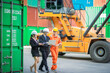 © nitinai2518 - Young executive visits the container storage yard to inspect the work with the personal secretary and foreman. Business and industrial concepts. Transportation and Logistics concepts.