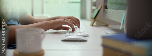 Fotomural Male entrepreneur typing on computer device on white office desk in modern offic