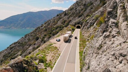 Wall Mural - aerial view on road with tunnel entrance mountains and sea view in mediterranean country trucks on roadside summer season