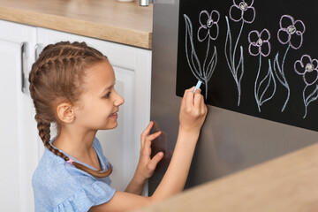 Canvas Print - Little girl drawing on chalkboard in kitchen