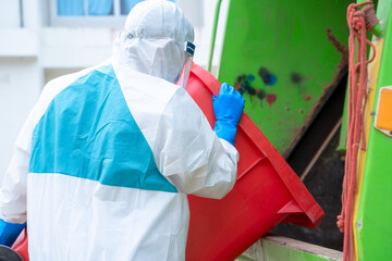 Wall Mural - Worker in hazmat PPE protective clothing wearing protective mask to Protect Against Covid-19 are loading waste with garbage collector truck.