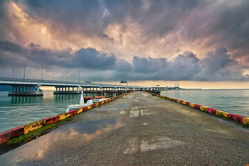 Wall Mural - Landscape view of a jetty with water pots reflecting bad weather clouds with penang second bridge as background