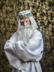 Wall Mural - A grey-haired bearded severe wizard in a white cloak is doing magic against dark-gold background.