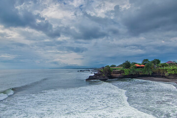 Poster - Great nature view of a beach in Tanah Lot Bali with waves hitting it during bad weather with negative space. Motion blur effect due to long exposure technique