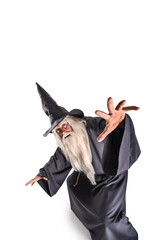 Wall Mural - A stern grey-haired bearded wizard in a gray cassock and a cap is practicing sorcery and doing magic against a light background.