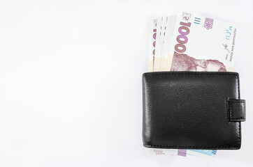 banknotes of 1000 hryvnias in a black men's wallet on a white background. Copy of space.