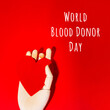 Wooden hand with big red heart in a giving gesture. World Blood Donor Day wording. Donation, help, health issues, antibody plazma concepts.