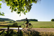 canvas print picture - Fahrradtour durch wunderschöne Odenwald Landschaft,
Frau fährt mit Elektro Fahrrad im letzten Sonnen Tageslicht.