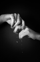 B & W hands of a woman dripping water with black background