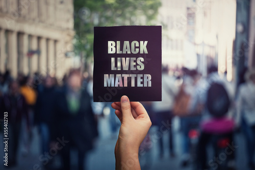 Plakat Black Lives Matter, demonstracja uliczna. Ludzka ręka trzyma ciemny sztandar protestu przeciwko niesprawiedliwości. Prawa Czarnych w USA, koncepcja problemów społecznych, rasizm i nierówność. Przestań dyskryminować.