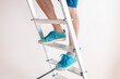 © Mihail - close up workers feet on the ladder climb to the top against the wall with copy space