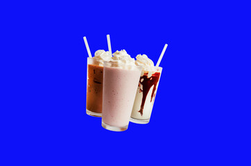 Glass of ice cream milkshake with chocolate on blue background