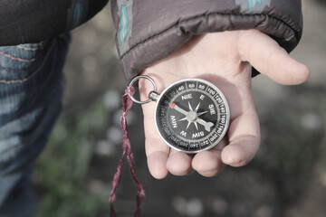 old classic navigation compass in childs hand on natural background
