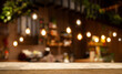 © Egor - Empty wooden table top on blur light golden bokeh of cafe restaurant, bar in a dark background.