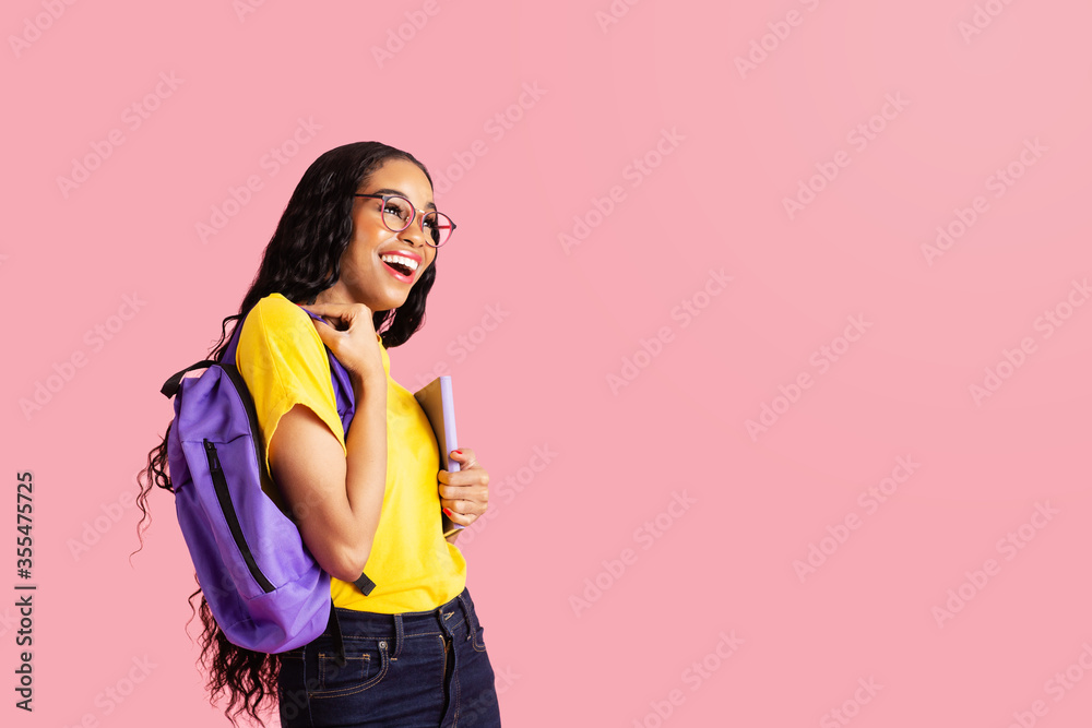 Portrait of a laughing young female student with book, backpack and ...