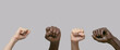 Black and white human hands with raised fists in the air on a gray isolated background. Close-up, banner, copy space. The concept of protest, violence and struggle.
