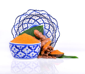 Canvas Print - Turmeric powder in a Thai pattern ceramic cup and in a wooden spoon complete with turmeric roots and leaves.herb for food and health.