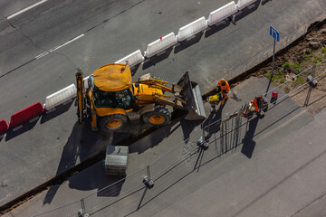 Repair work on the city streets using a heavy loader with a bucket for the construction of the road. Construction site for road works - top view. Public works, civil engineering, road construction.