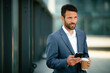 © JustLife - Portrait of handsome businessman. Man using phone.