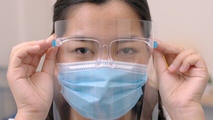 Portrait of an Asia young female who is wearing a face shield with mask rounded around her face from a frontal perspective to protect her glasses and eyes prepare to new normal. Coronavirus pandemic.