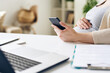© pressmaster - Hand of young pregnant businesswoman using smartphone by desk