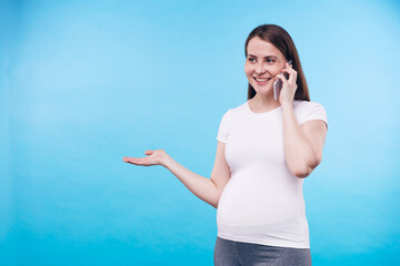 Canvas Print - Smiling pregnant woman with smartphone by ear talking to her friend