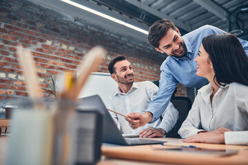 Wall Mural - Co-workers sitting at office desk with laptops and talking