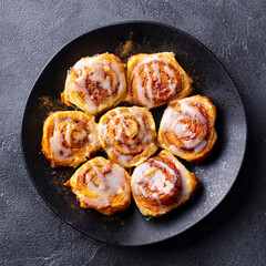 Wall Mural - Cinnamon rolls on black plate. Dark background. Close up. Top view.