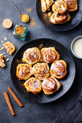 Wall Mural - Cinnamon rolls on black plate. Grey background. Top view.