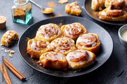 Fotomural Cinnamon rolls, buns on black plate. Dark background. Close up.