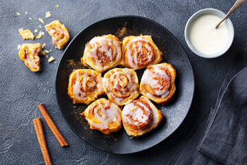 Wall Mural - Cinnamon rolls on black plate. Grey background. Close up. Top view.