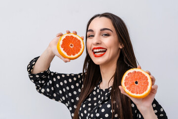 Canvas Print - Cute woman with red lips. Woman holding citrus fruit halves in hands showing to the camera. Facial expressions.