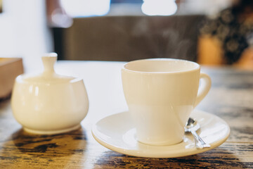 Aromatic fresh coffee in a white cup. Espresso in a small white cup and a sugar bowl in a summer cafe. Fragrant fresh coffee in a restaurant.