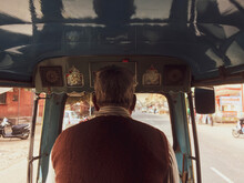 Back View Of An Old Man Driving A Tuk Tuk Taxi In The Streets Of Nepal