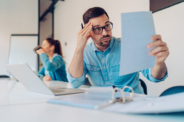 Wall Mural - Exhausted businessman reading contract in the office