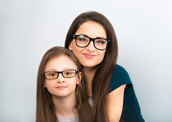 Wall Mural - Happy young casual mother and positive smiling kid in fashion glasses hugging on light blue background with empty copy space. Closeup