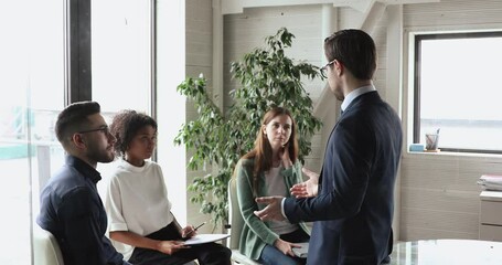 Poster - Businessman executive wearing suit teaching diverse business team at corporate training. Confident caucasian male manager teaching multicultural workers group explaining marketing project at office