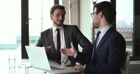 Wall Mural - Two smiling male business partners handshake use laptop find partnership solution. Happy successful businessmen shake hands agree on ebusiness service integrity network growth at office meeting.