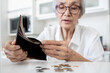 © Satjawat - Female senior holding empty wallet,old people shaking out money coins in wallet,financial problems in the retirement age of elderly,planning savings,poverty during Coronavirus crisis,economic downturn