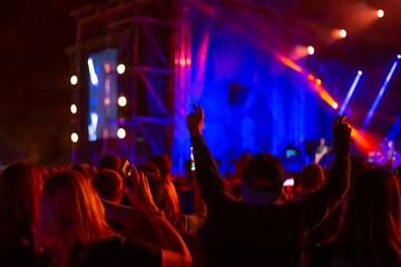 crowd of fans raise their hands up and dance in a night club, a concert and bright illumination, leisure and entertainment