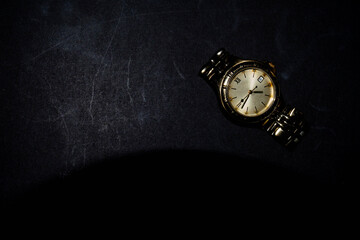 Gold watch placed on a black background. Business concepts and time. There's a copy space.