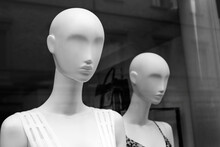Portrait Of Two Fashionable White Bald Female Mannequins In A Shop Window. Black And White Photo.