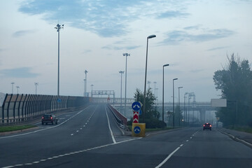 Wall Mural - Road junction. Ascent to the bridge. Road leads to the motorway. Concept - road architecture. Highways in the Mist. One of the roads leads to the bridge. City landscape. Concept driveway construction